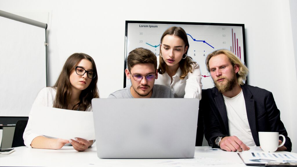 jeunes qui observent un ordinateur avec un graphique financier en arrière plan