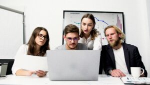 jeunes qui observent un ordinateur avec un graphique financier en arrière plan