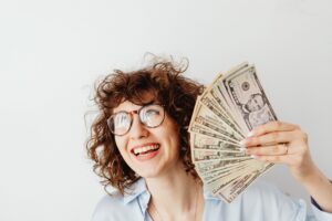 jeune femme qui tient une liasse de billets en souriant